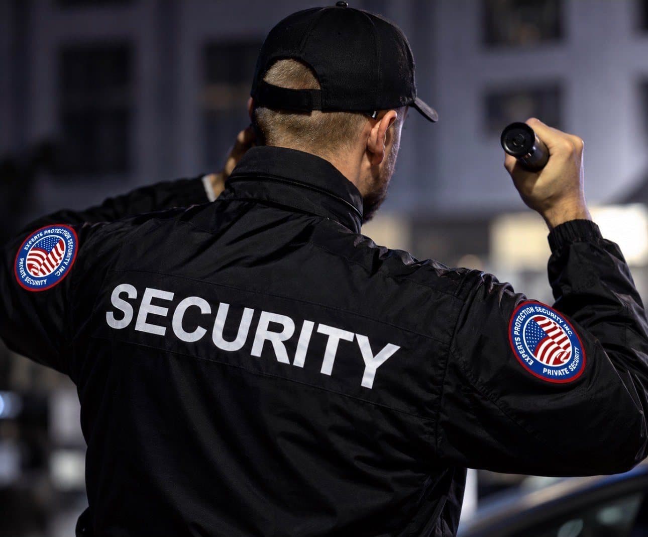 Officer on a night patrol in a black SECURITY jacket with company patches on both shoulders